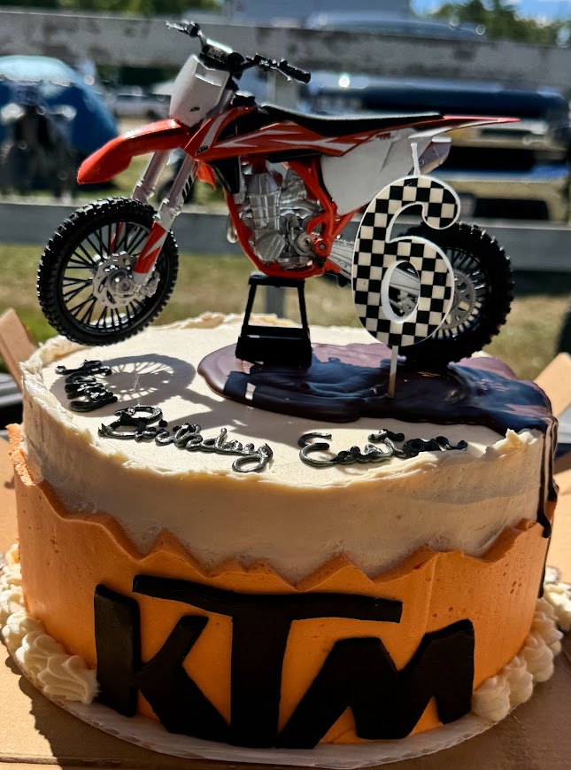 Orange and white KTM-themed cake with a dirt bike topper and number six